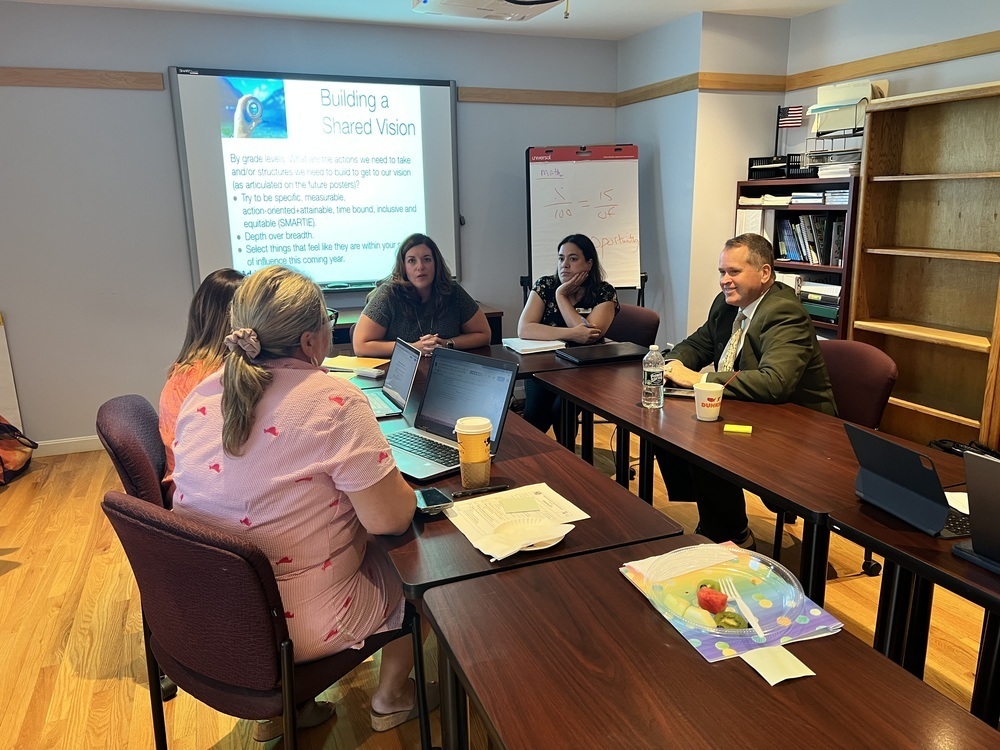 Superintendent Bill Runey meeting administrators in a room.